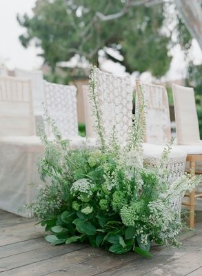 the chairs are lined up with flowers and greenery