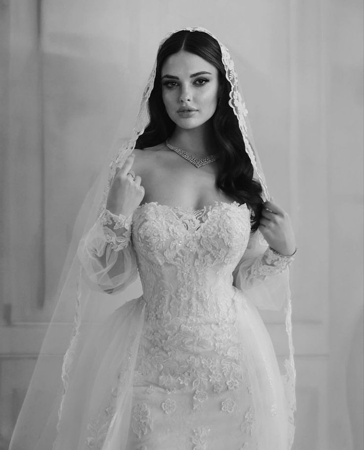 a woman in a wedding dress and veil posing for the camera with her hands on her hips