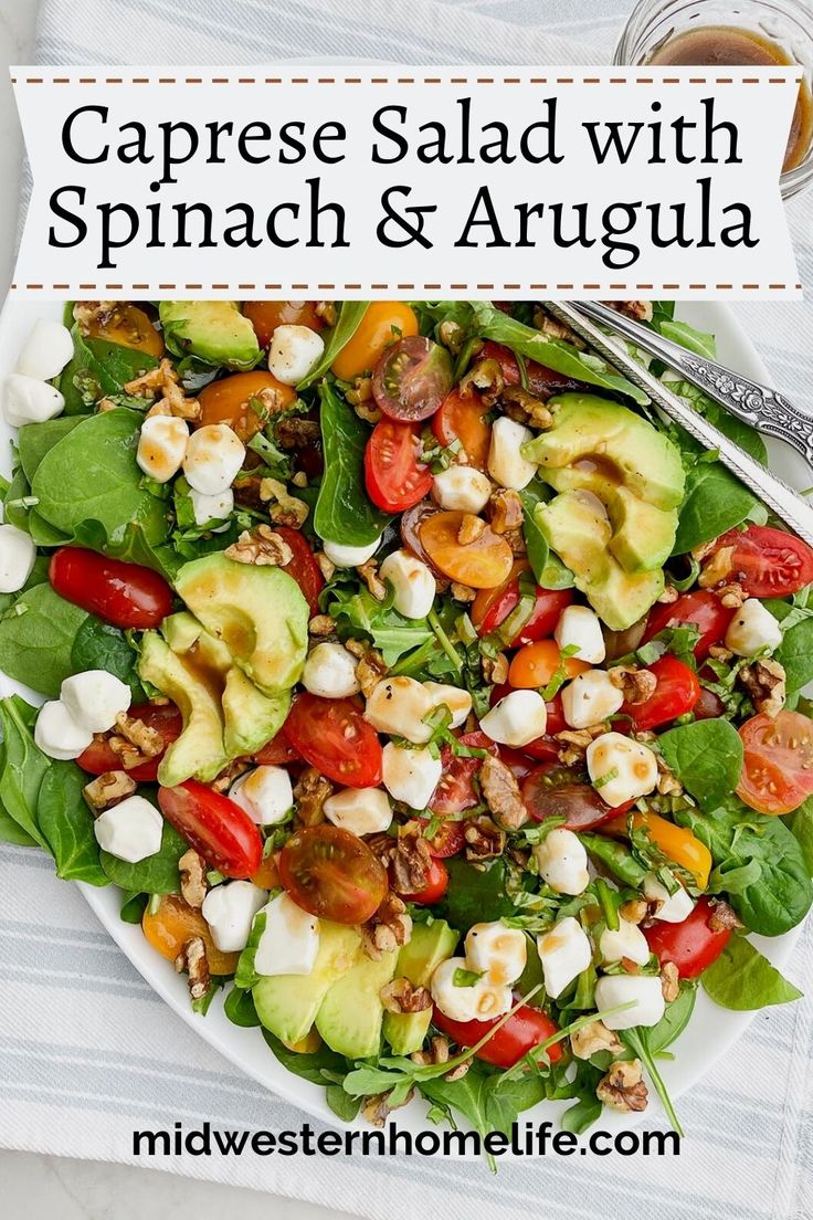 caprese salad with spinach and arugula on a white plate next to a cup of coffee