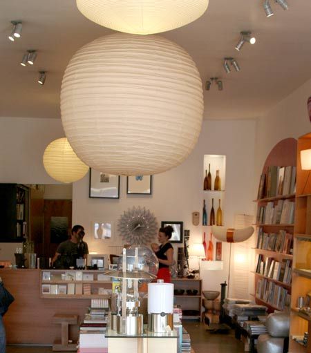 the interior of a store with lots of books on shelves and lamps hanging from the ceiling