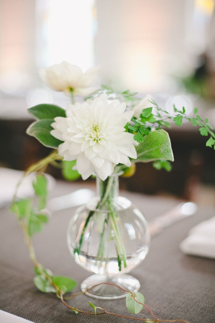 two vases with white flowers in them on a table