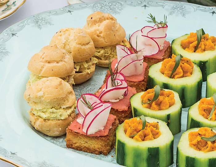 a plate with cucumber sandwiches and other food items on it, including pickles