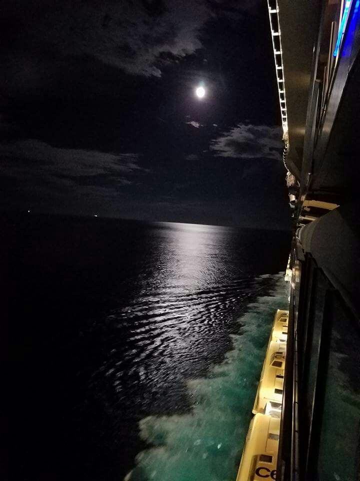 the moon is shining over the ocean as seen from a boat on the water at night