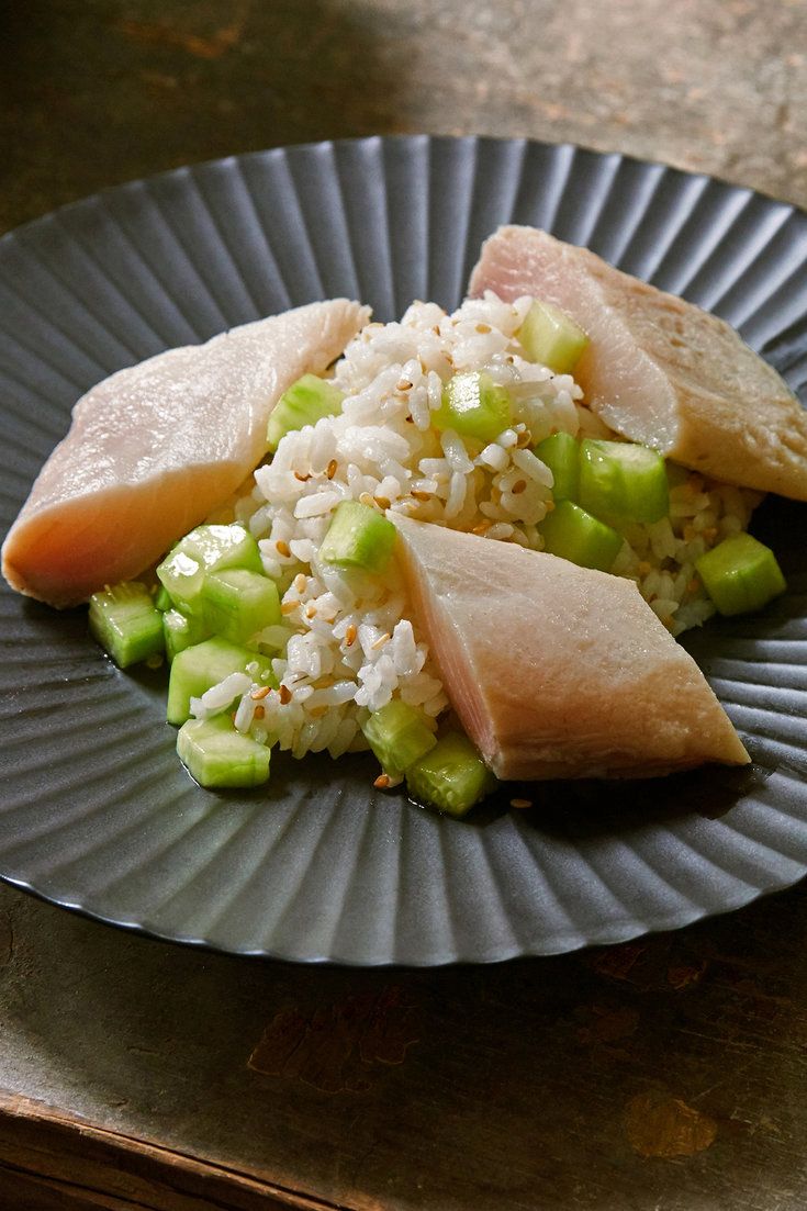 a plate with rice, cucumber and fish on it sitting on a table