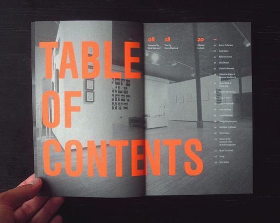 a hand holding an open book with the words table of contents printed on it in orange