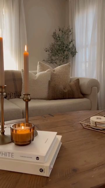 two candles are sitting on top of a book in front of a couch and coffee table