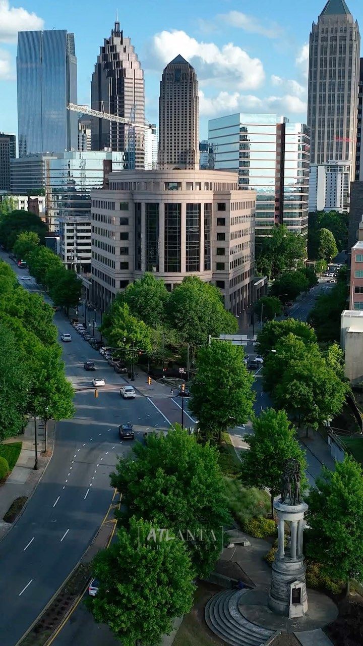 an aerial view of a city street with tall buildings and trees in the foreground