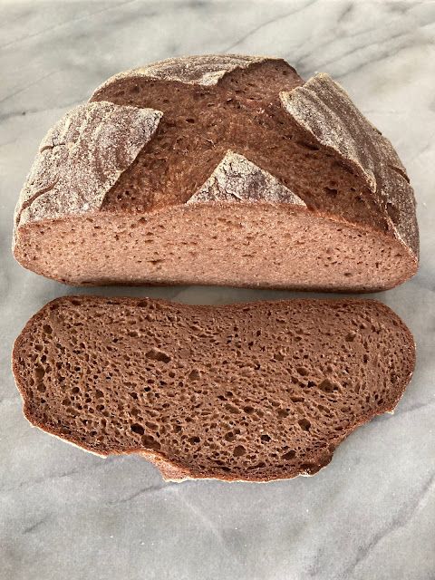 a loaf of bread sitting on top of a marble countertop next to a slice of bread