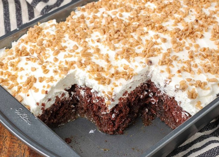 a chocolate cake with white frosting and nuts on top is shown in a pan