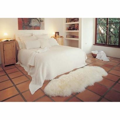 a white bed sitting in a bedroom on top of a floor next to a window