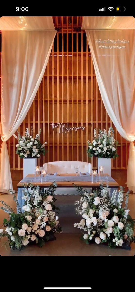 a table with flowers and candles in front of an open screen backdrop for a wedding ceremony