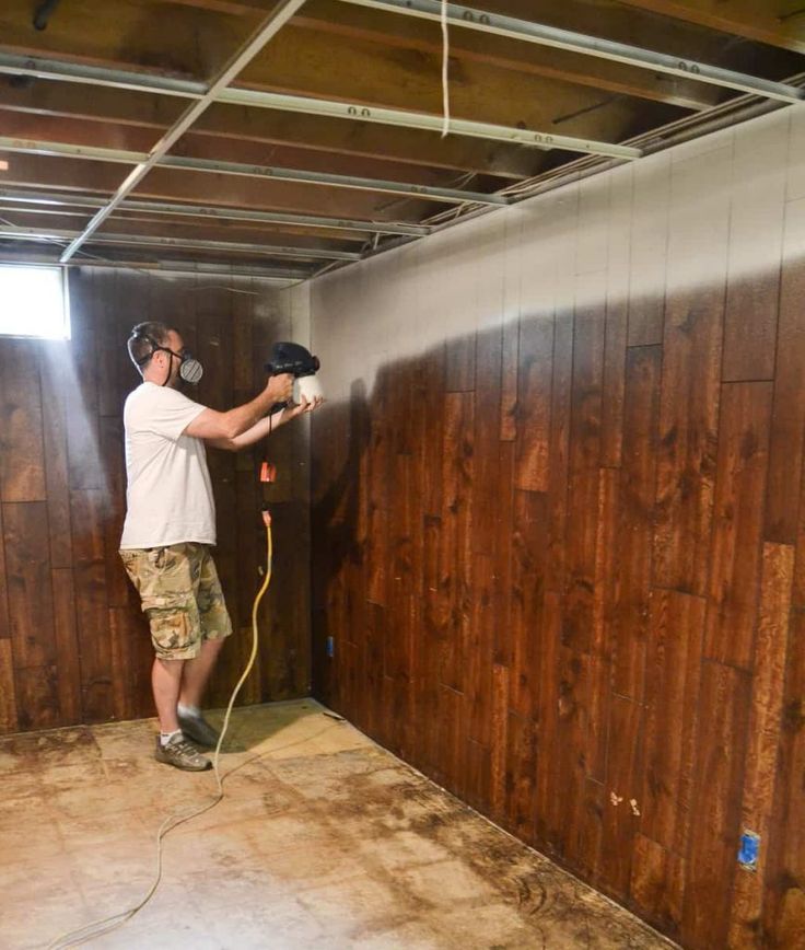 a man is using a power drill to install wood paneling in a room with no walls