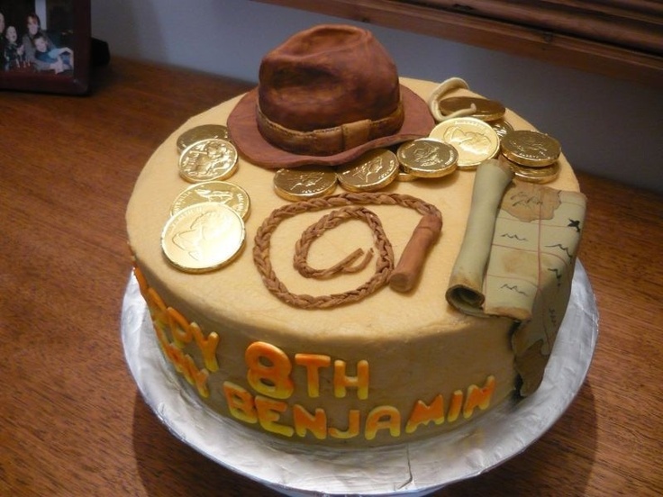 a birthday cake with coins and a hat on it's top, sitting on a table