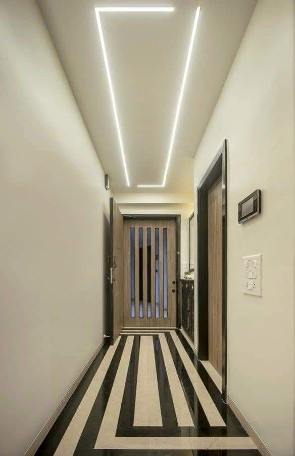 an empty hallway with black and white stripes on the floor is lit by recessed lighting