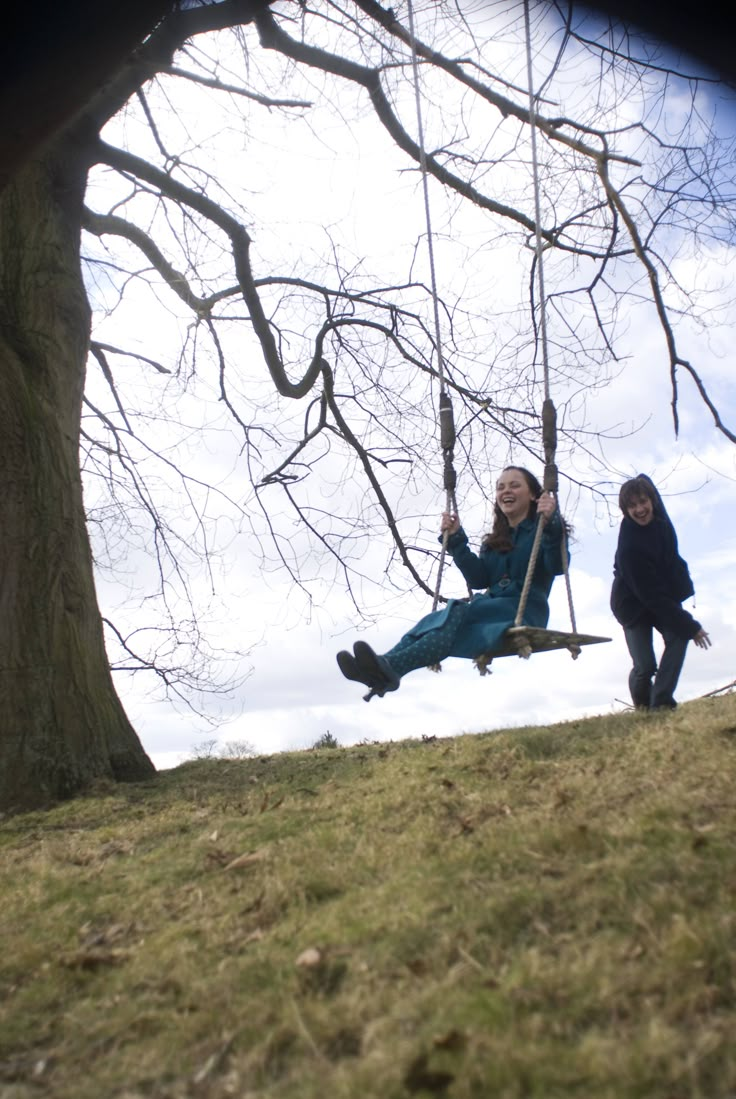 two girls are playing on swings in the park