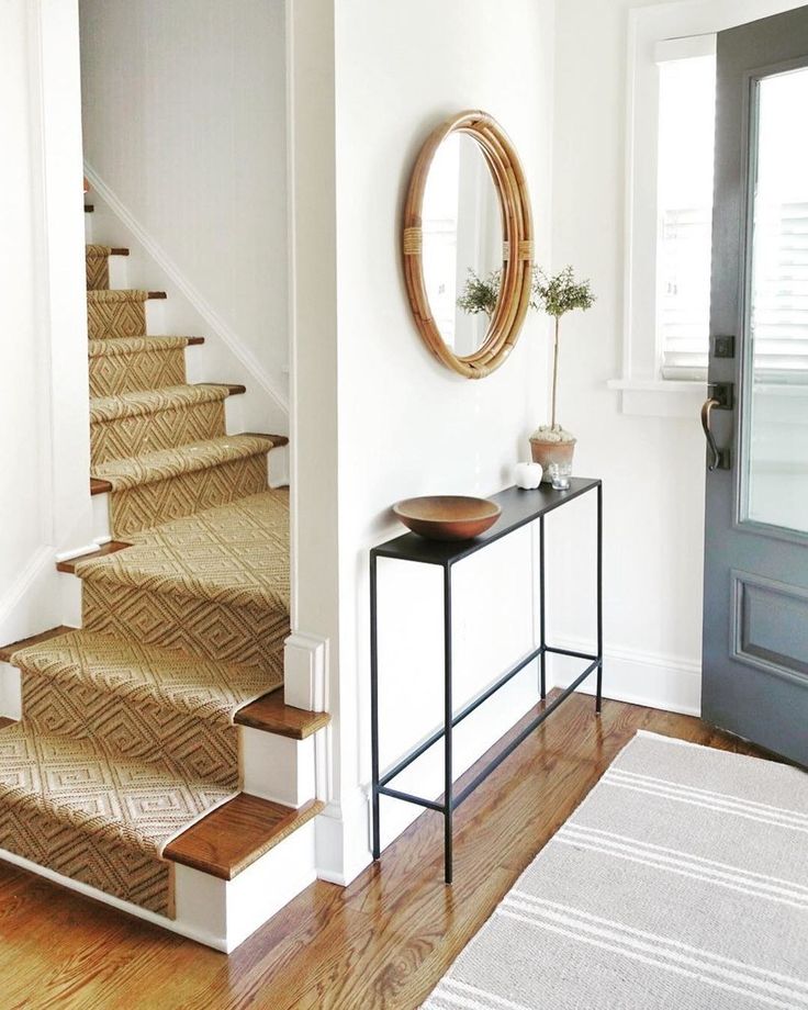 there is a mirror on the wall next to some stairs and a table with a plant in it