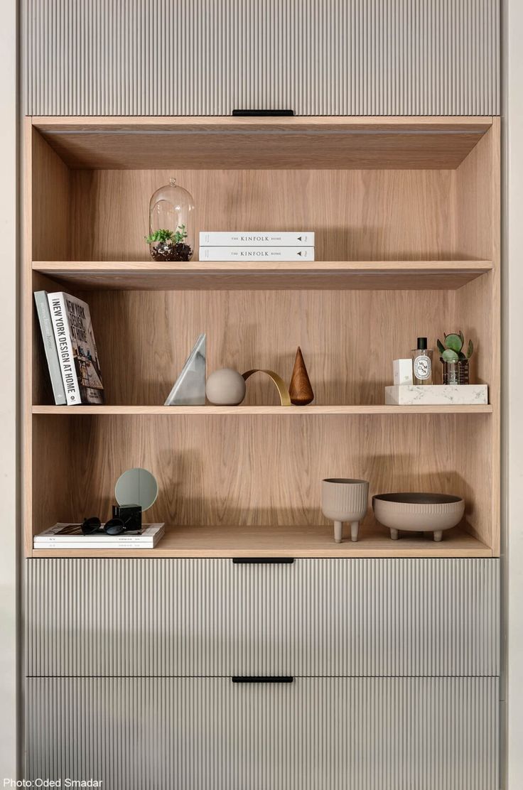 an open book shelf with books and vases on the top shelves in front of it