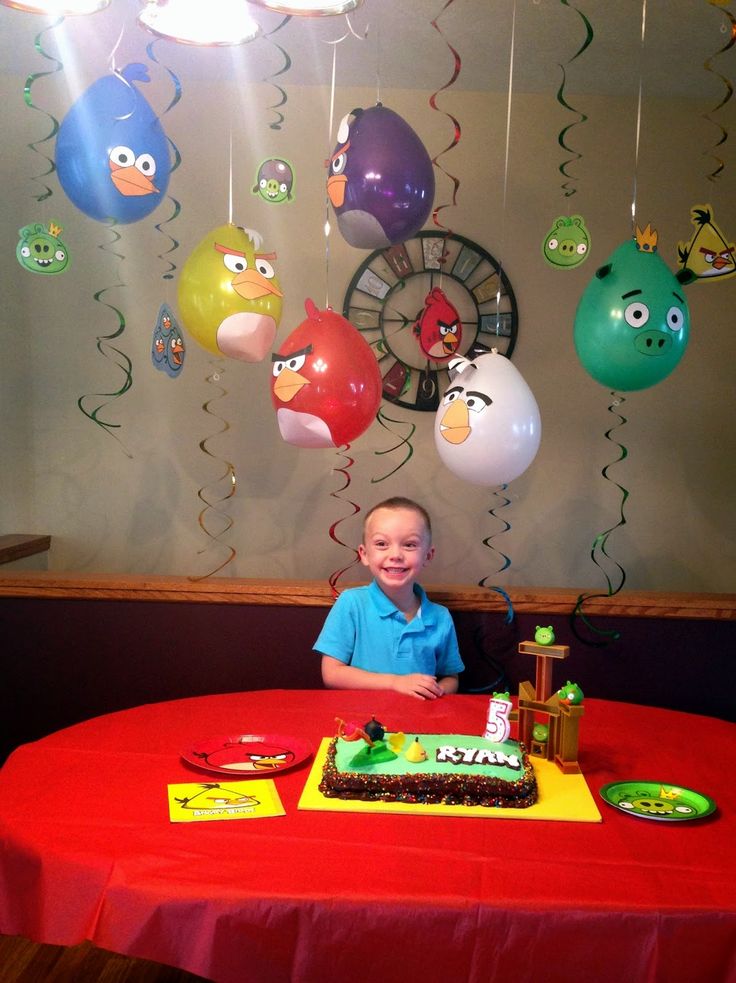 a young boy sitting at a table in front of a cake with angry birds on it