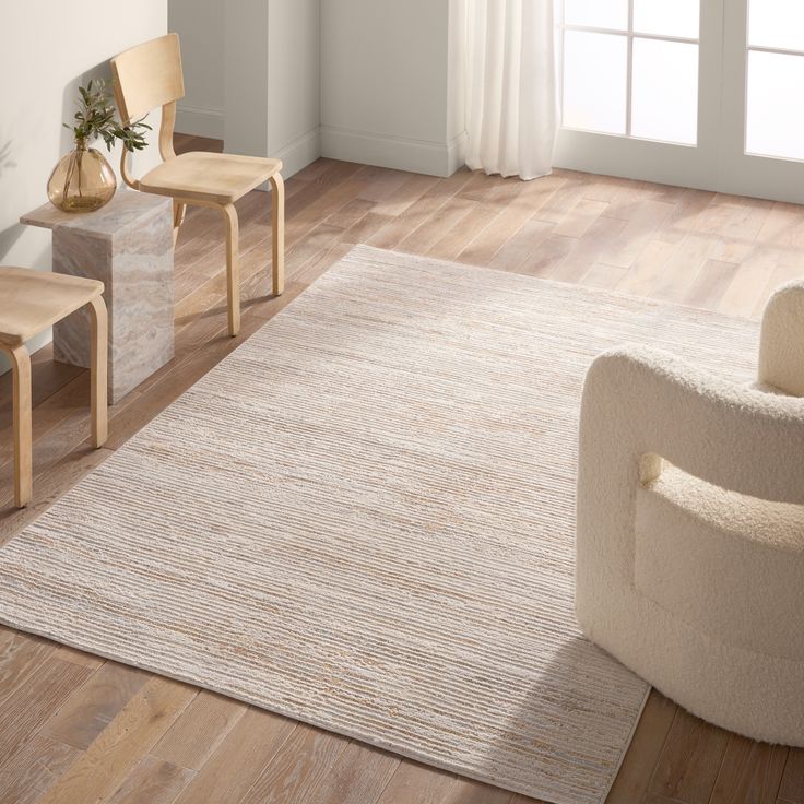 a living room scene with focus on the rug and two chairs in front of it