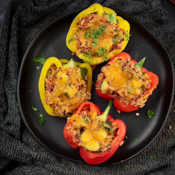 three stuffed bell peppers on a black plate