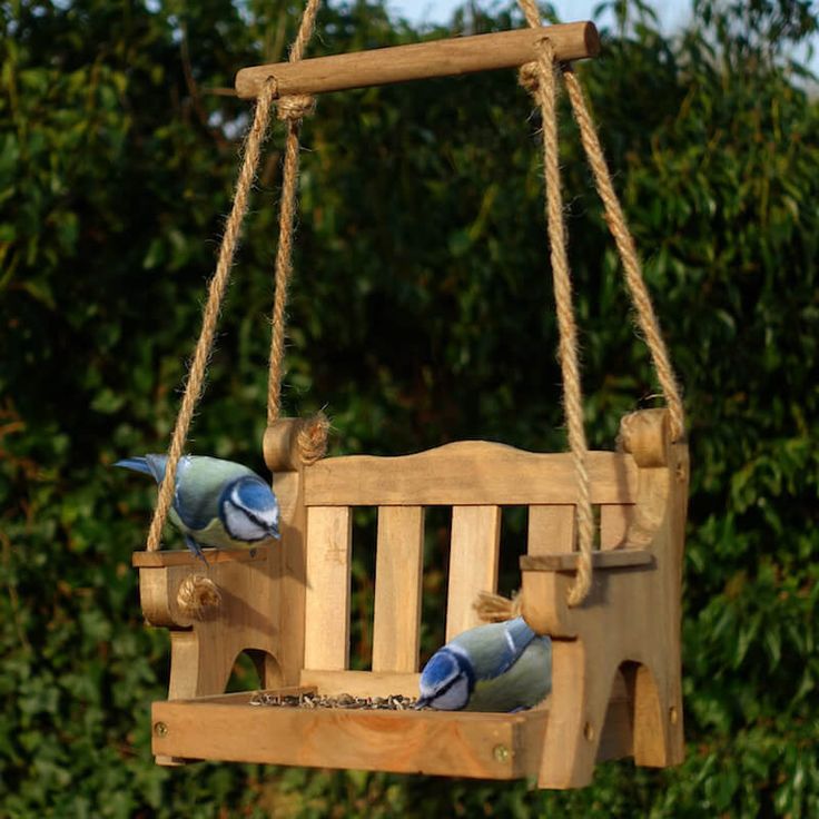 a wooden swing with two blue birds on it