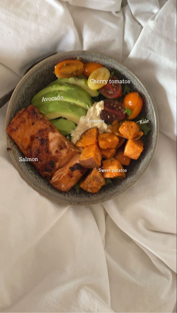 a bowl filled with meat and vegetables on top of a white bed sheeted surface