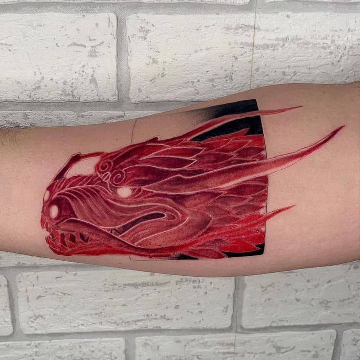 a man's arm with a red dragon tattoo on it