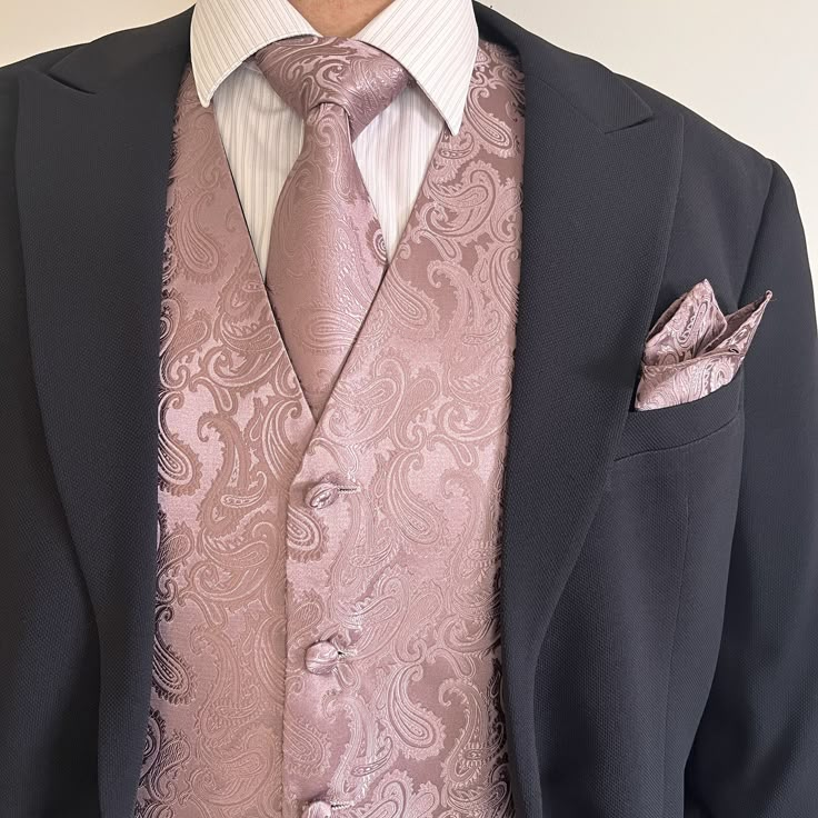 a man in a suit with a pink tie and pocket square on his lapel