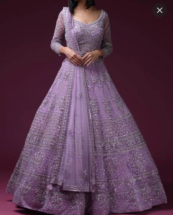 a woman in a purple gown with long sleeves and an intricate pattern on the skirt