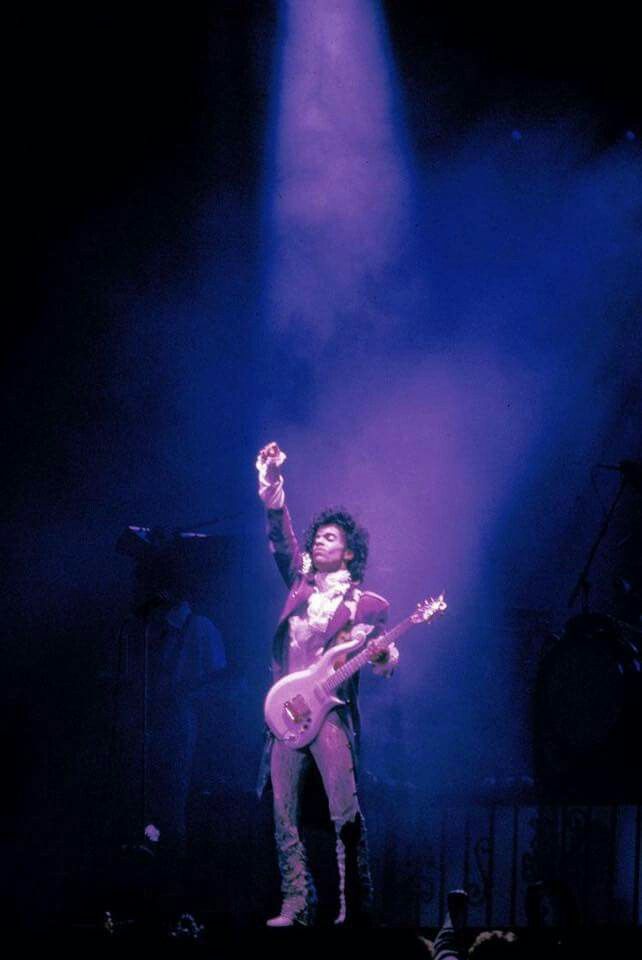 an image of a man that is on stage with a guitar in his hand and lights coming from behind him