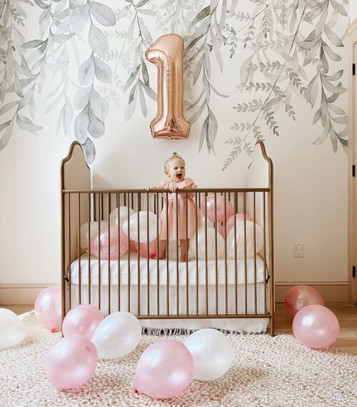 a baby girl in her crib with balloons