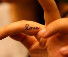 a person's hand with the word love written on it and two fingers in the foreground