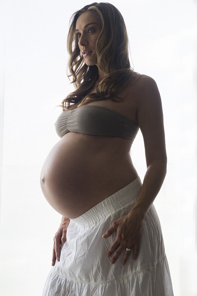 a pregnant woman in a white skirt posing for the camera