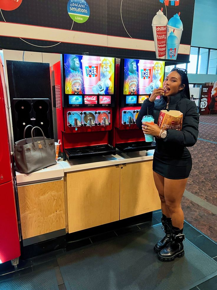 a woman is standing in front of some vending machines and eating something out of her hand