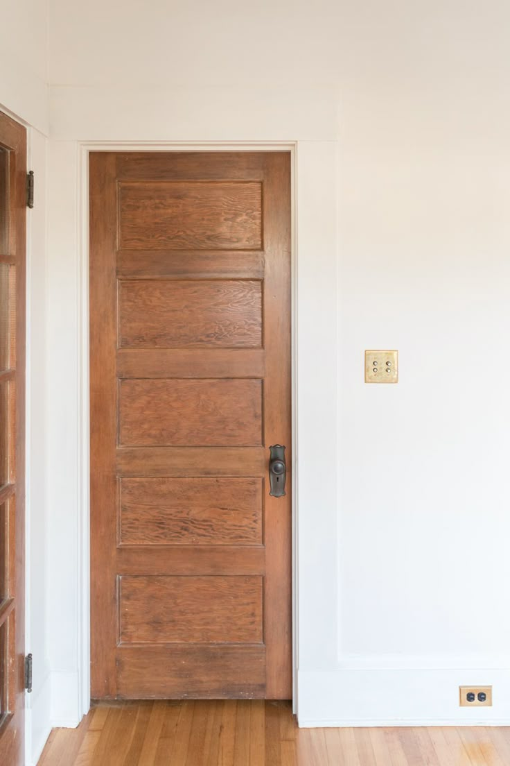 an empty room with a wooden door and hard wood floor