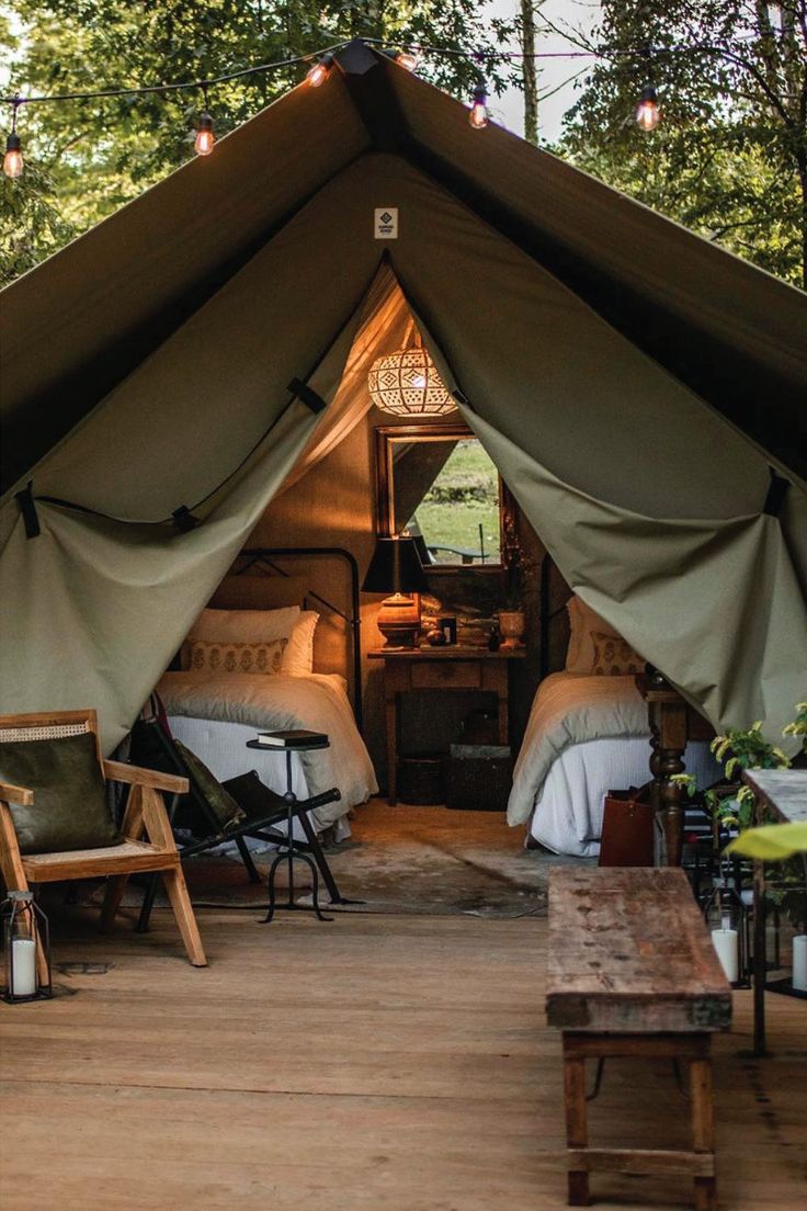 the inside of a tent with two beds in it and chairs on the floor outside