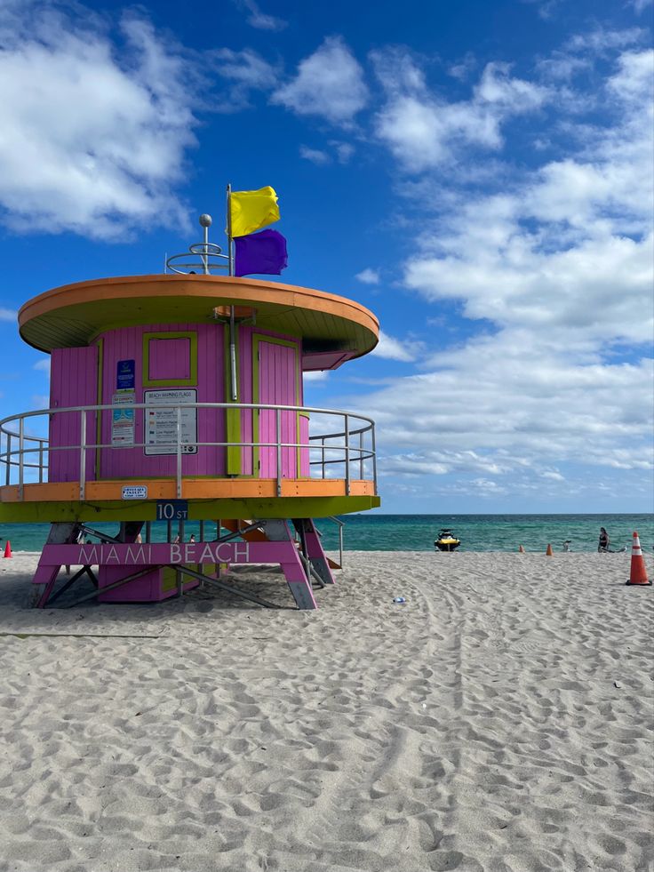 a lifeguard tower on the beach with people swimming in the water