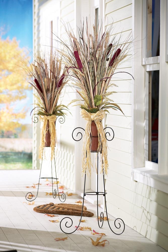 two metal planters with plants in them on the front door porch, next to an open window