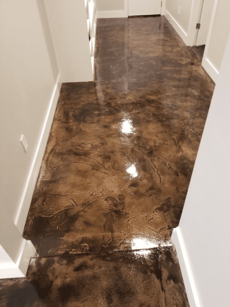 an empty hallway with white walls and brown flooring in the center is dirty from rain