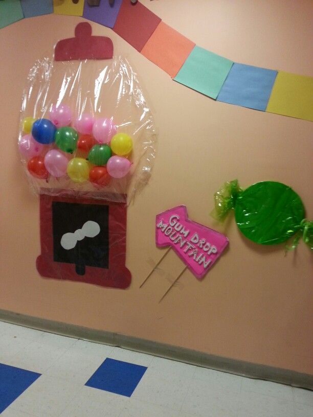 there is a candy machine on the wall with balloons in front of it and a sign that says sweet gummy