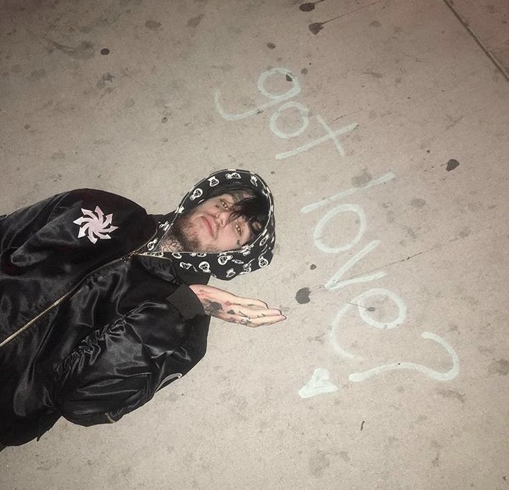 a man is laying on the ground with his hand up in front of him while wearing a black jacket