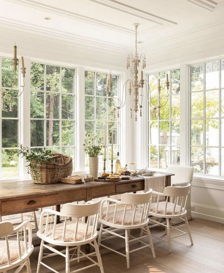 a dining room table with white chairs and windows