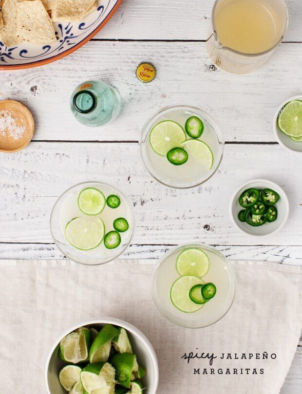 two bowls filled with cucumber and lime slices on top of a white table