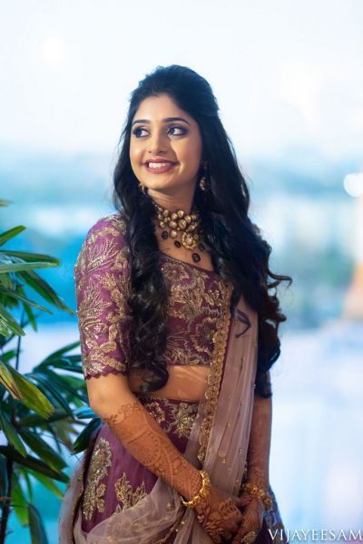 a woman in a purple and gold sari posing for the camera with her hands on her hips