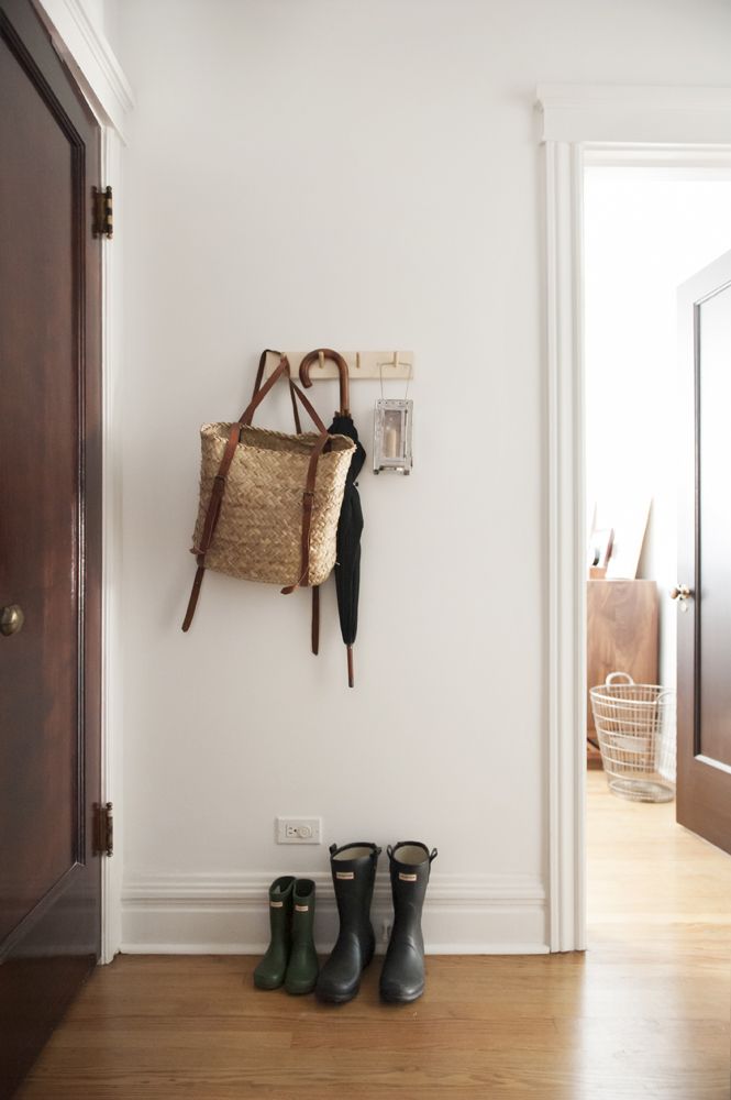 two pairs of rain boots sitting on the floor next to a wall mounted coat rack