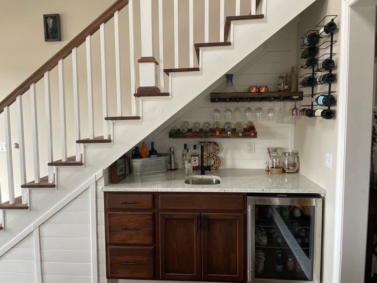 a kitchen under the stairs with wine bottles on it