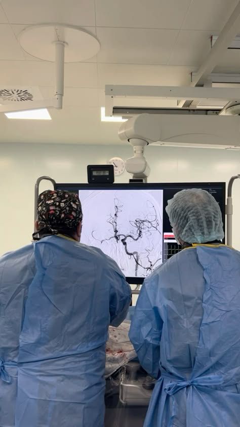 two doctors in scrubs looking at an x - ray image on a monitor screen