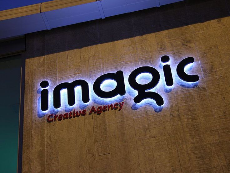 an illuminated sign on the side of a building that says imagine creative agency at night