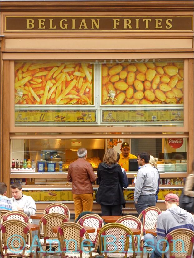 people are standing in front of a store with chairs and tables outside the window looking at food