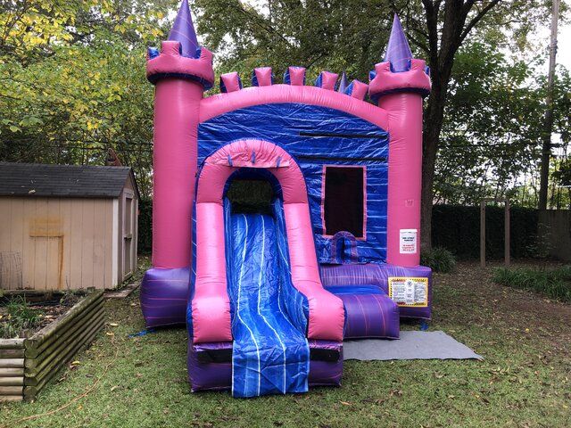 a bouncy castle with a slide in the back yard for kids to play